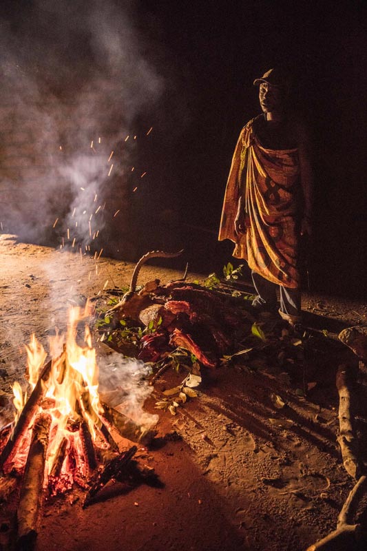 A man from a local village preparing bushmeat (poached antelope) on a fire outside his home. Preparing bushmeat right after a kill is essential to ensure that the meat is safe to eat. An antelope can feed a family for weeks and all parts of the animal will be used by the family.